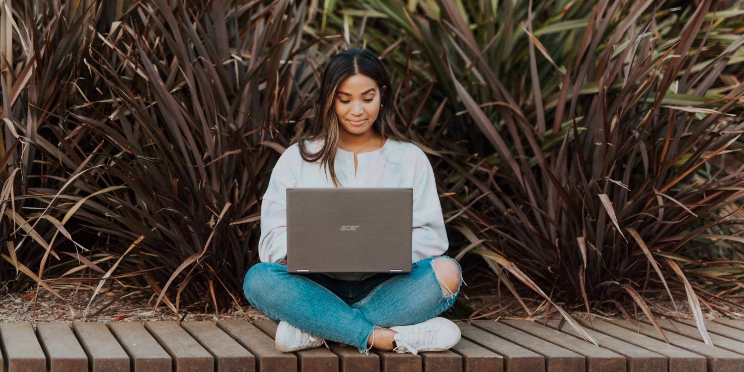 a student smiling and sitting with their laptop in their lap 