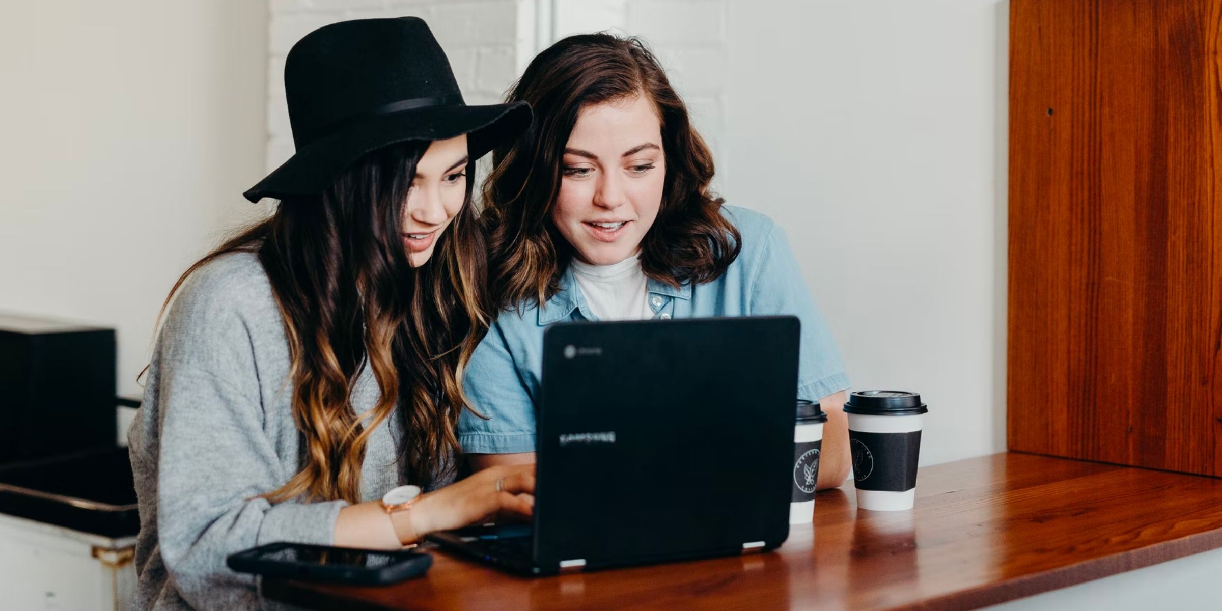 two students smiling at a laptop