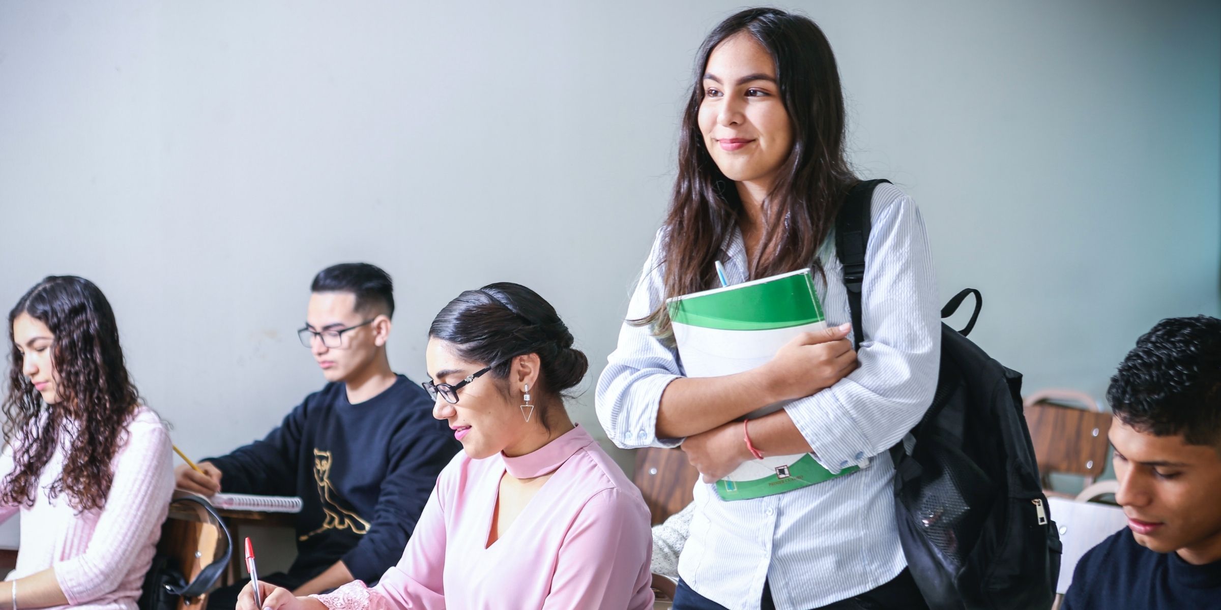 a standing student smiling among seated students in a classroom