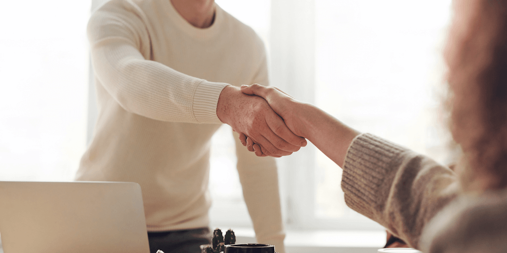 Two people shaking hands with their heads out of frame.