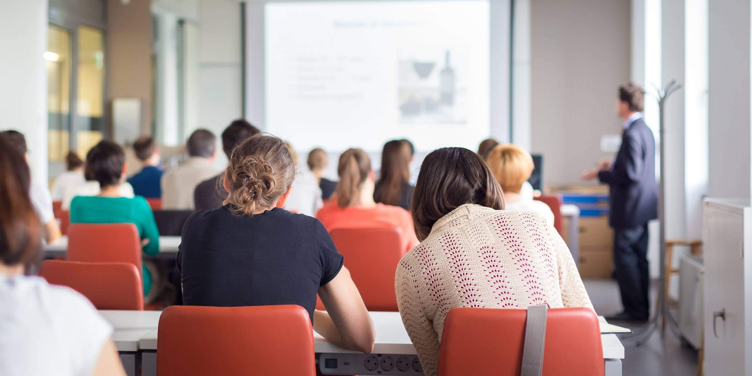 the backs of several students in orange chairs within a classroom