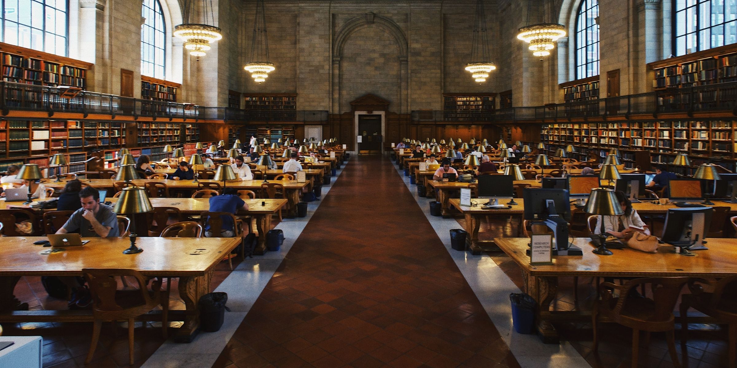 rows of students studying in a large campus library 