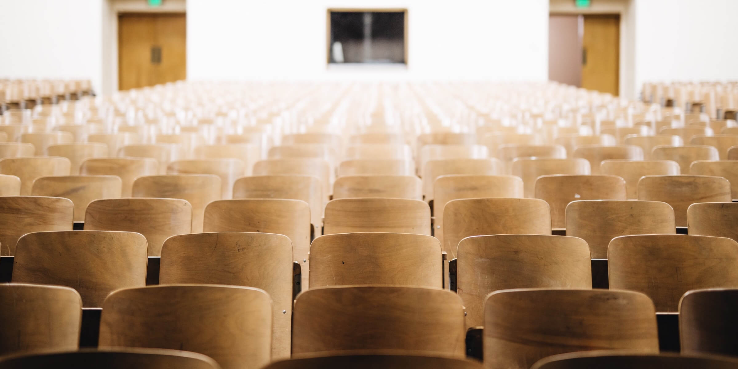 dozens of empty seats in a large college lecture hall