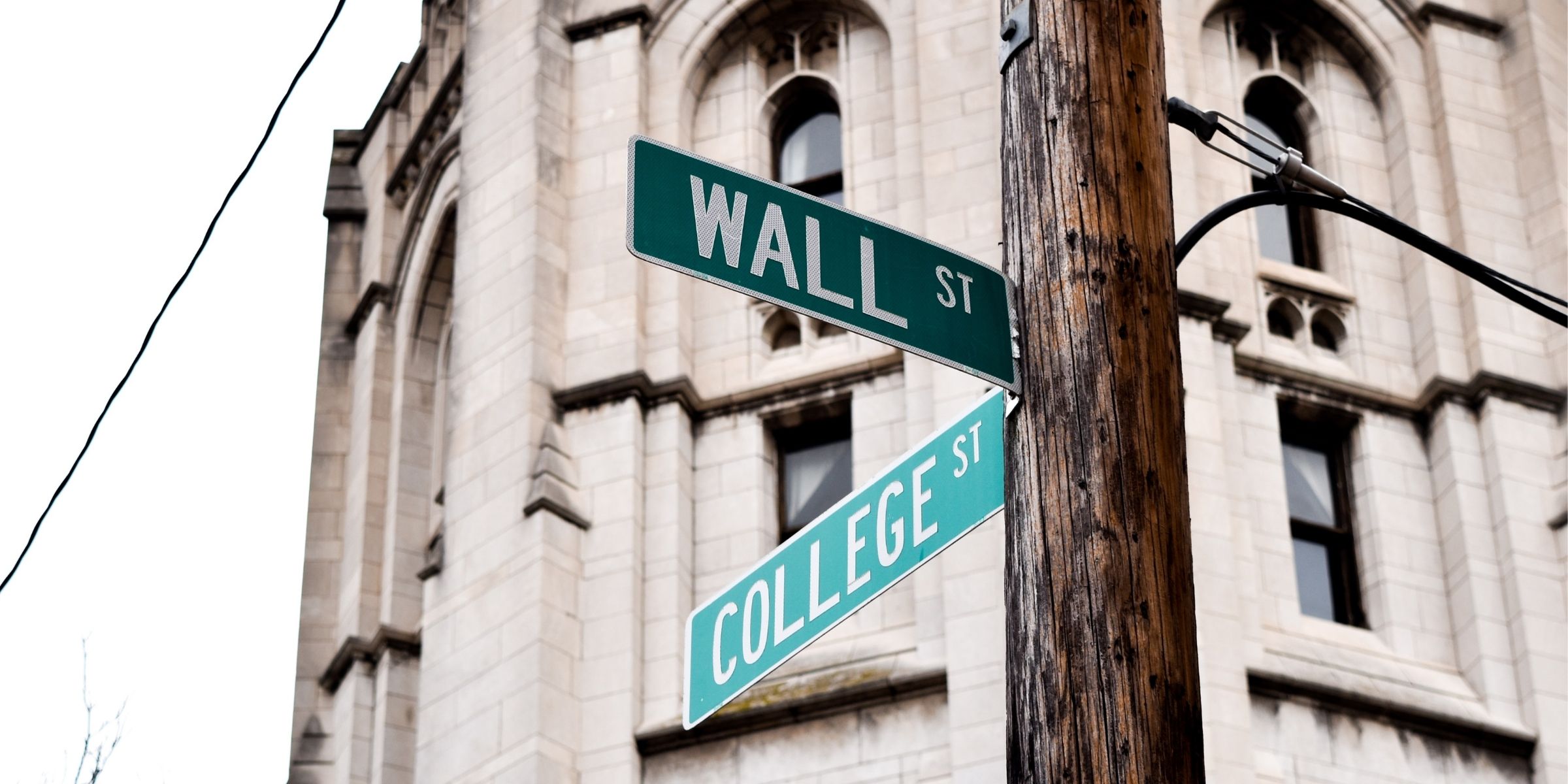 a street cross section with one sign that says College Street and another that says Wall Street