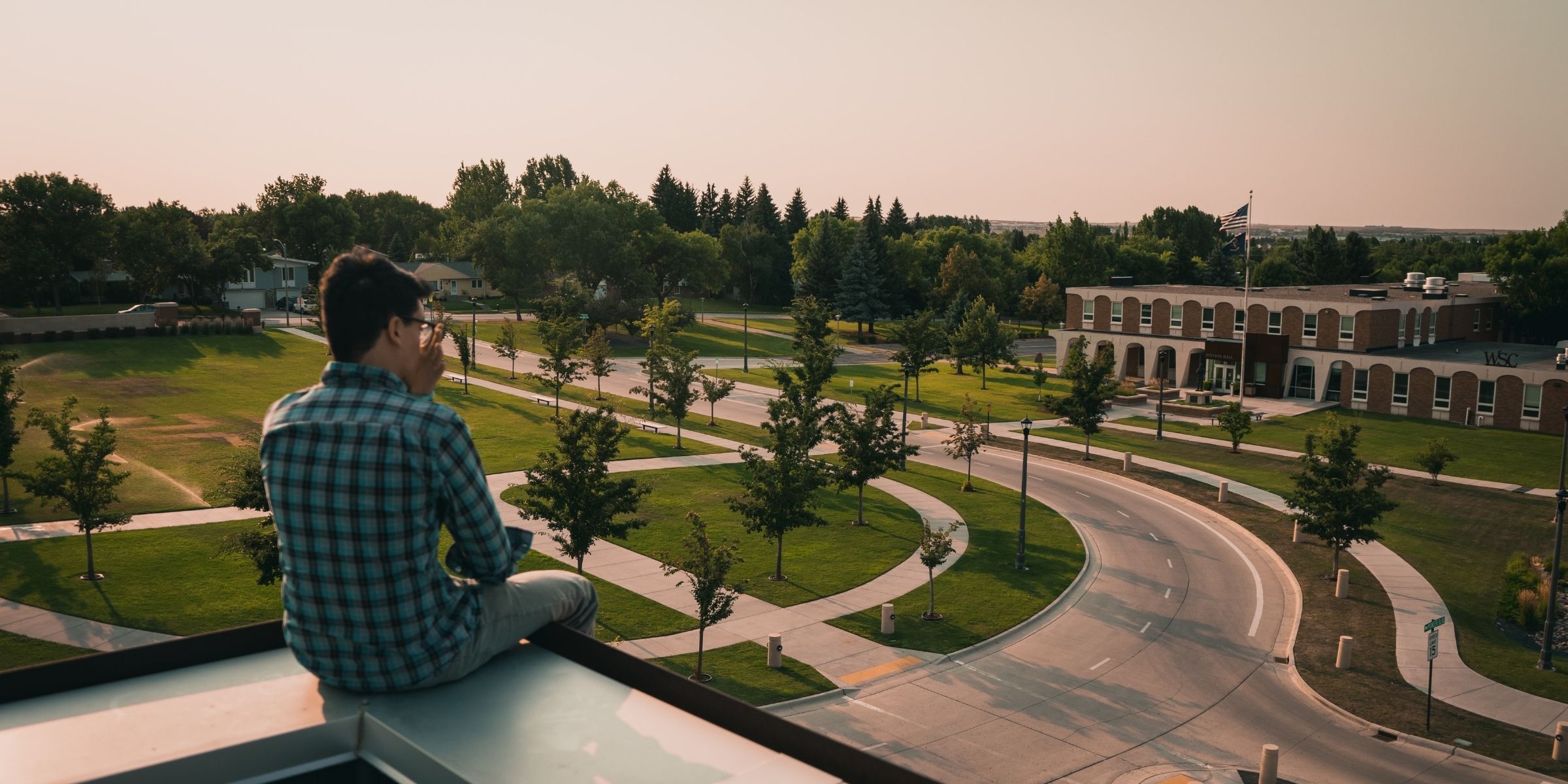 a student sitting outdoors overlooking a college campus