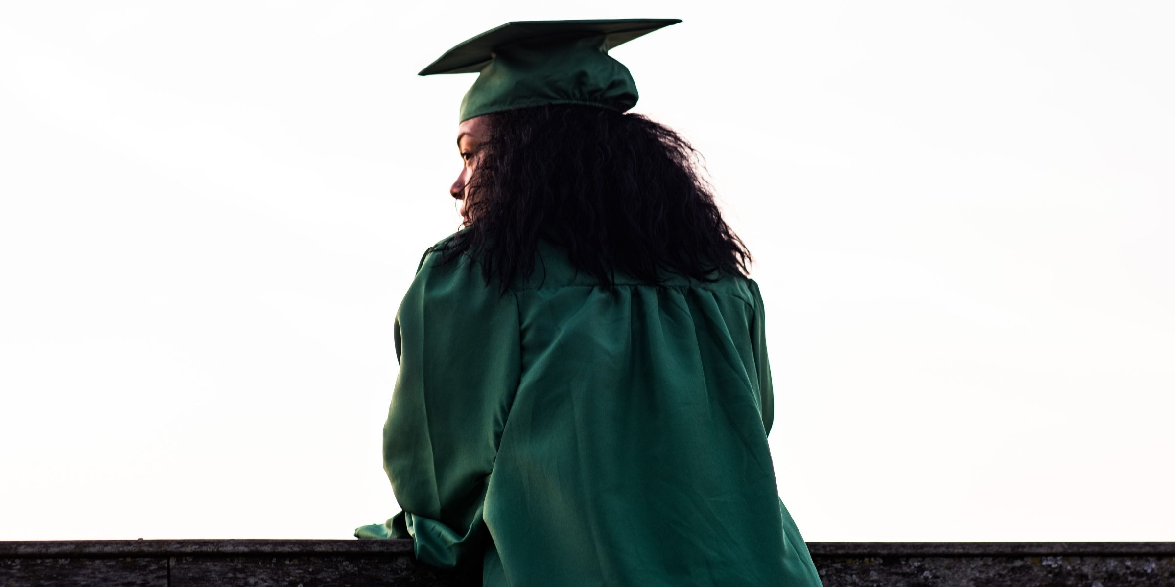 a student wearing a graduation cap and gown looking away from the camera