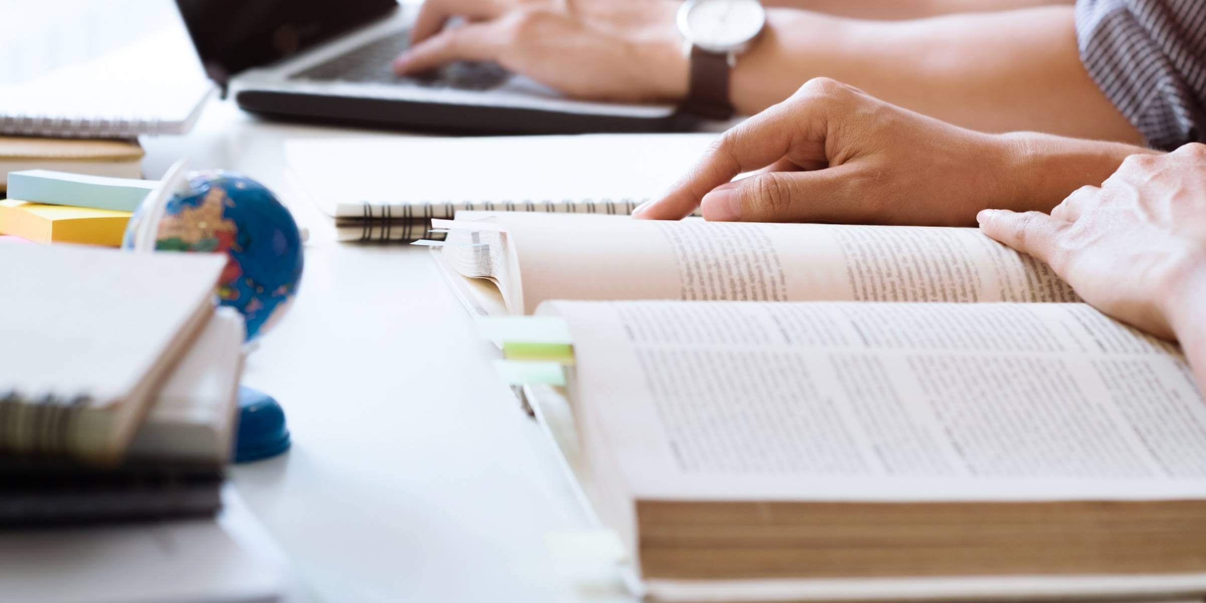 closeup of a student's hands by an open book