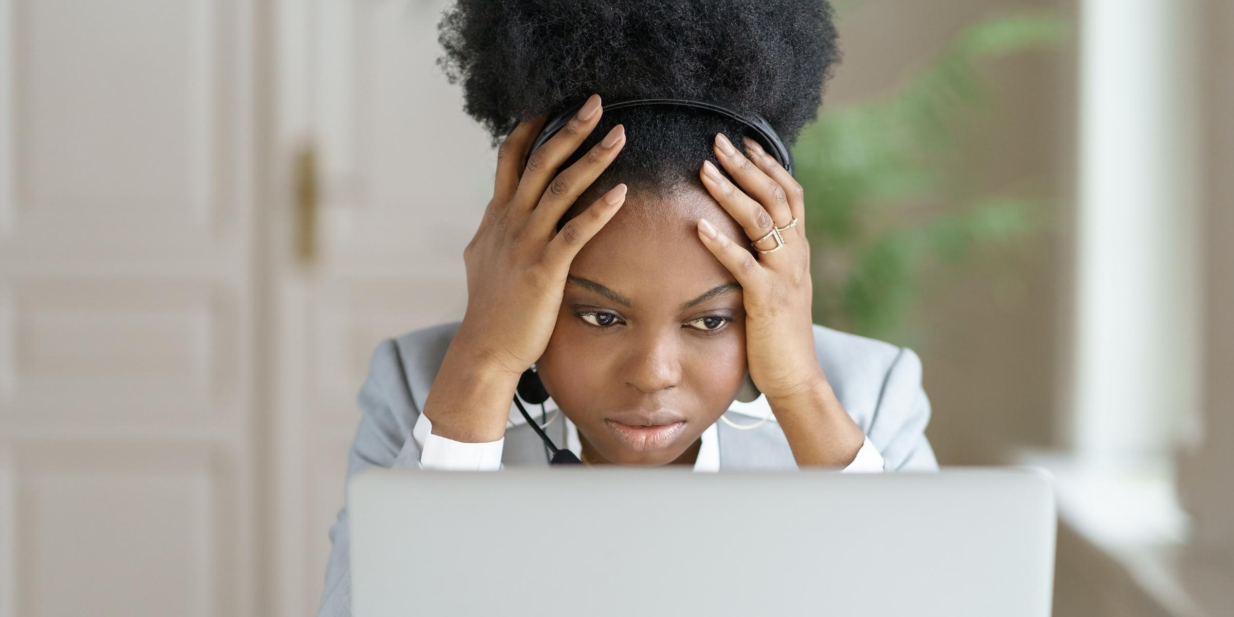 a person looking frustrated at a laptop with her hands on her head 