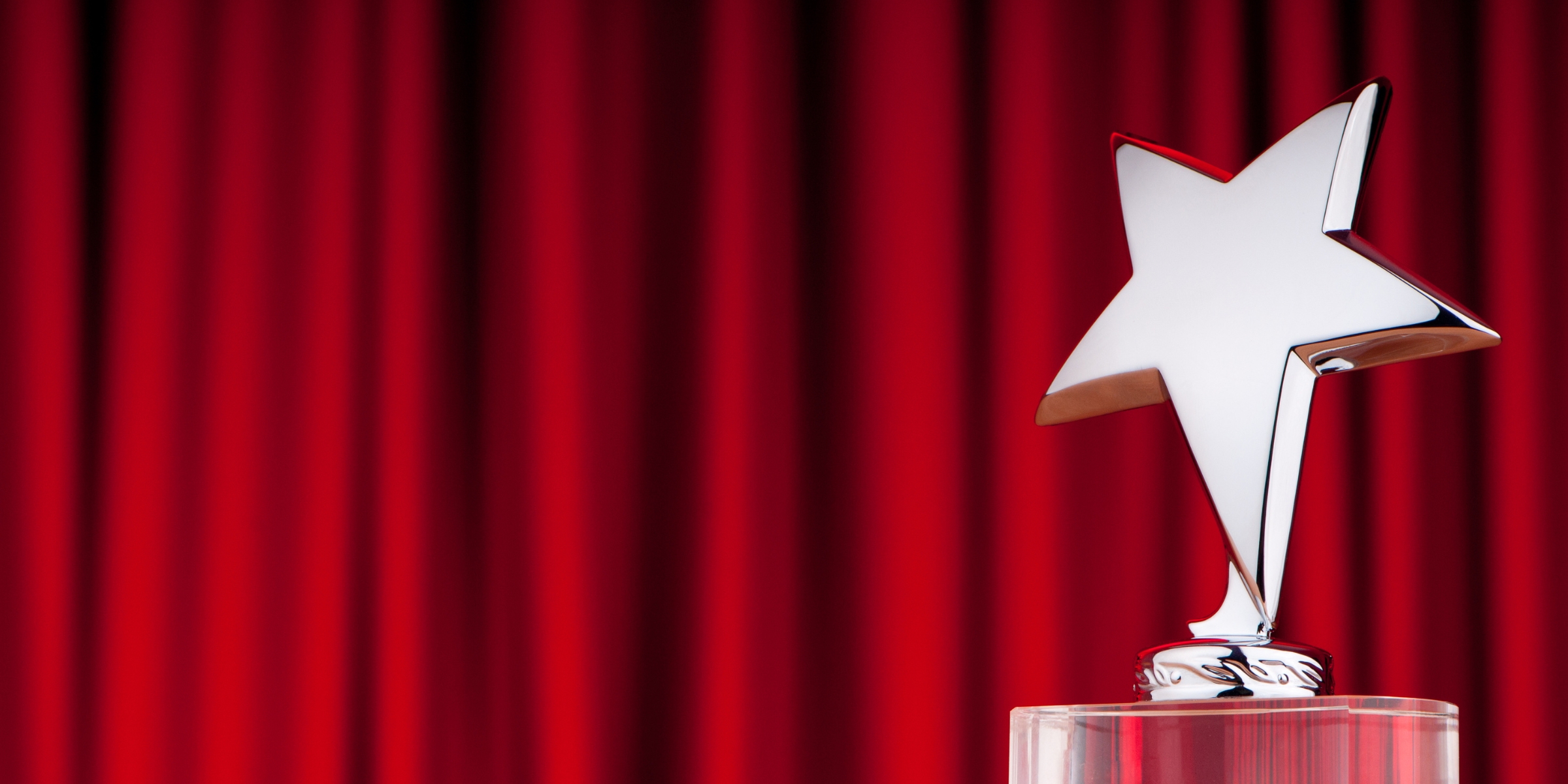 a silver star-shaped trophy in front of a red curtain
