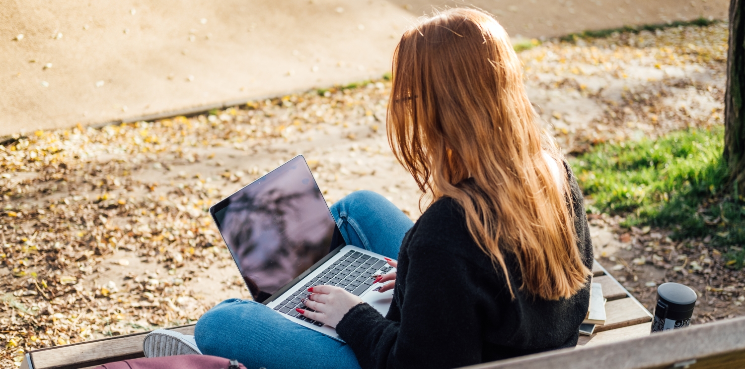 a student sitting outside with a laptop