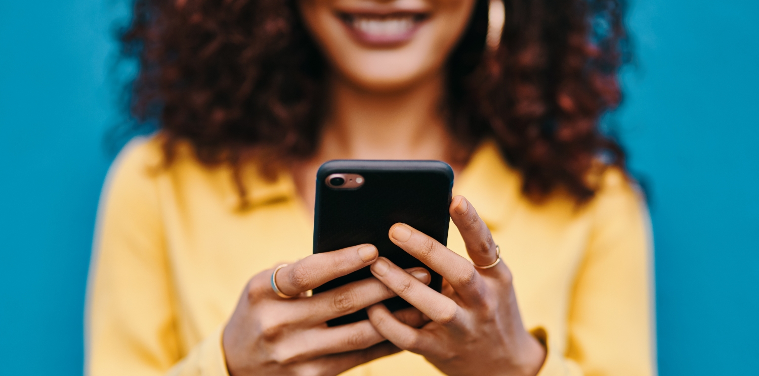 closeup of a person holding their cell phone in front of them and smiling