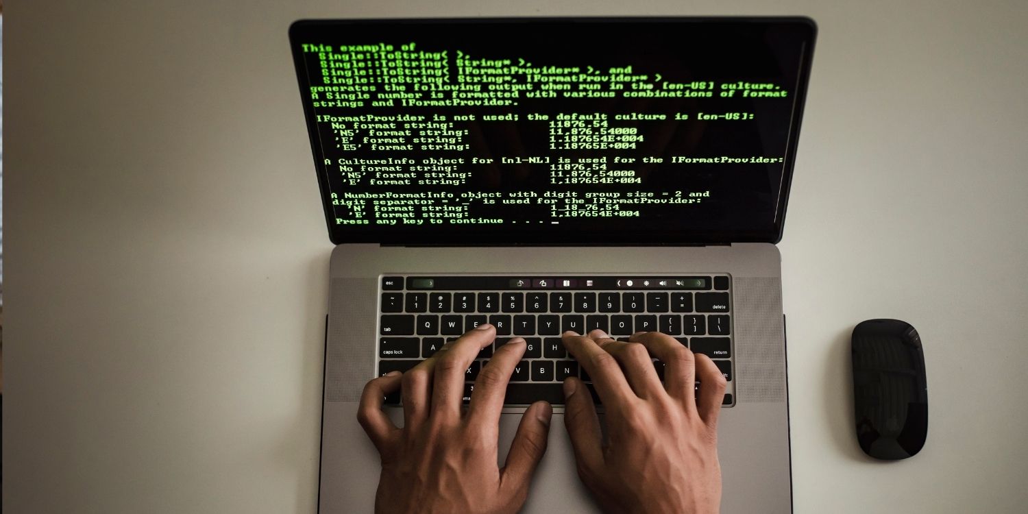 hands typing on a laptop showing computer code
