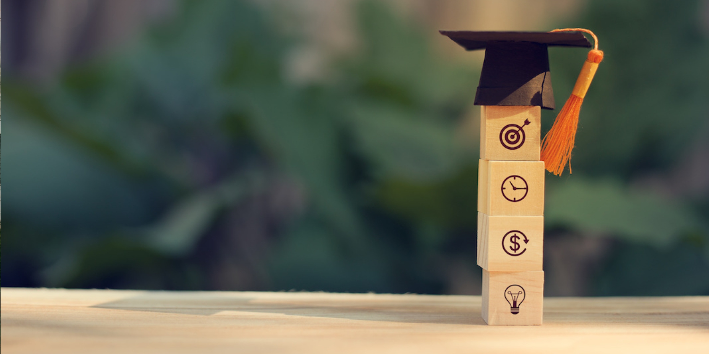 a graduation cap above 4 stacked wooden blocks